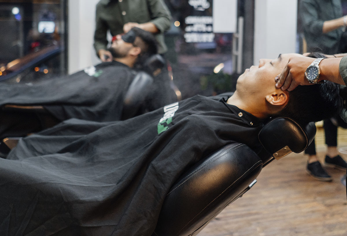 Foto de dos clientes siendo atendidos en barbería Verouomo